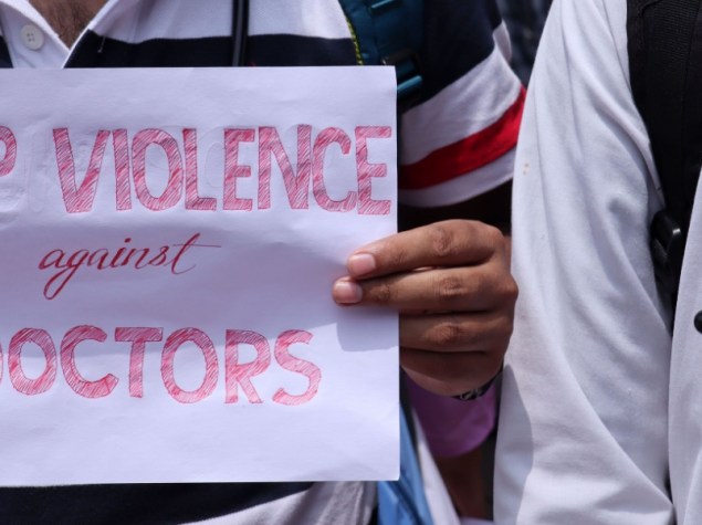 donna a mezzo busto che tiene cartello con scritto "stop violence against doctors"