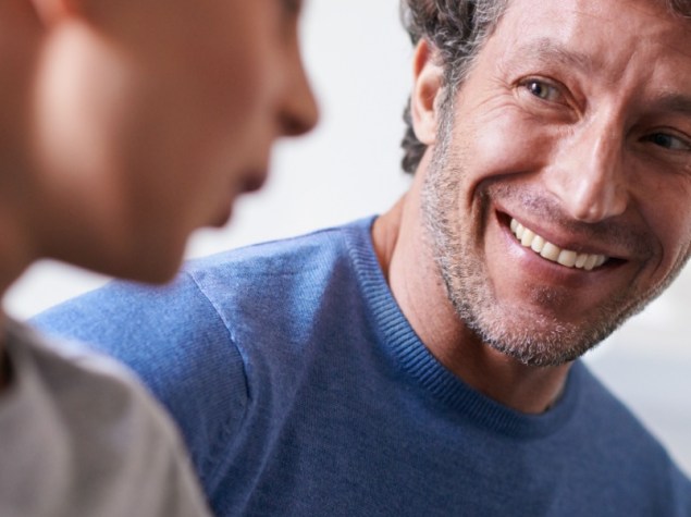 Padre sorride e parla con figlio adolescente