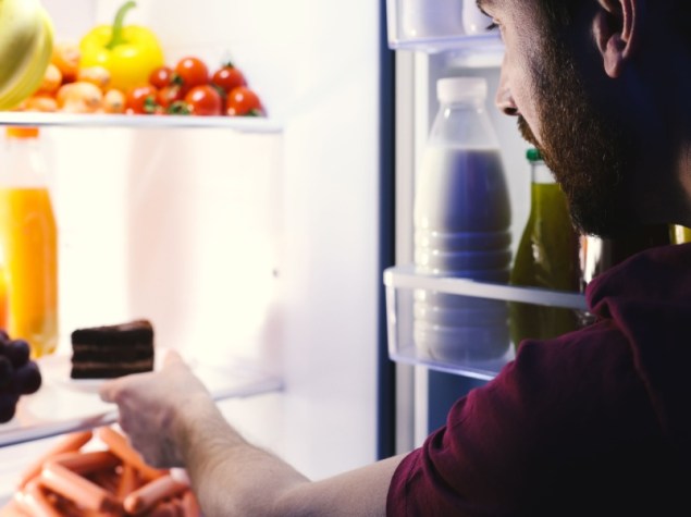 Uomo prende cibo dal frigorifero di notte