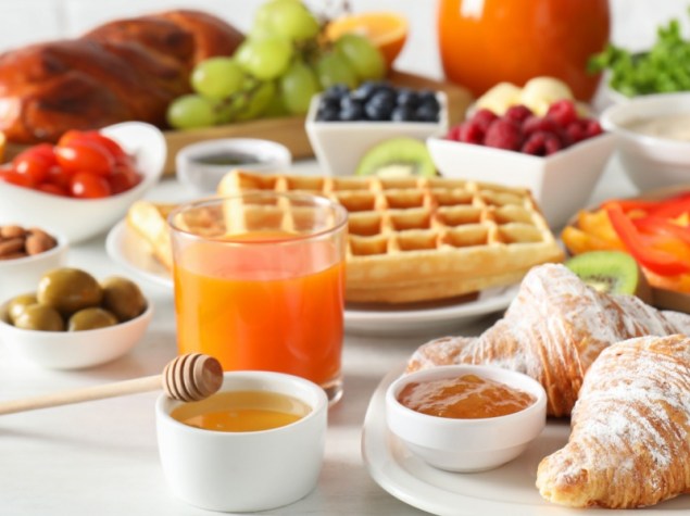 Tavolo imbandito per colazione con cornetti, frutta fresca e bevande