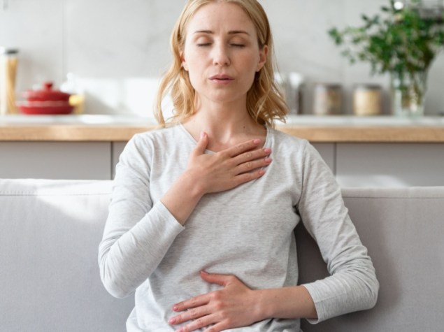 Donna sul divano fa esercizi respiratori