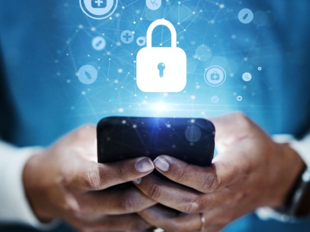 dottoressa che tiene tra le mani un dispositivo mobile da cui compare l'ologramma di un lucchetto