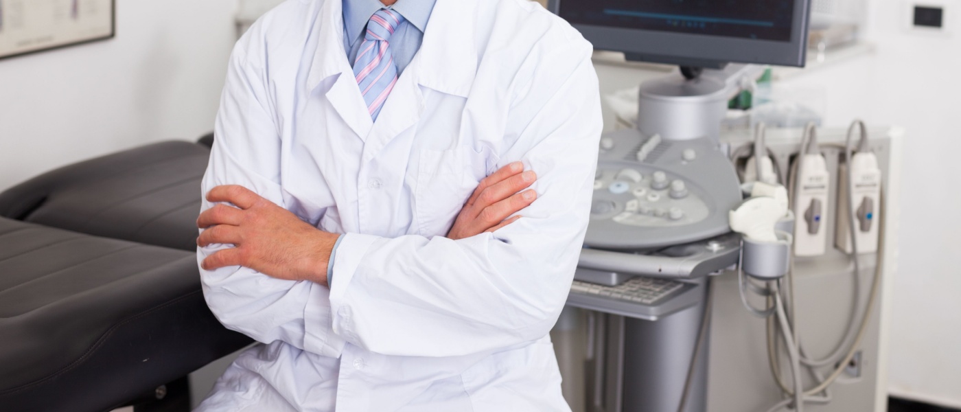 Ritratto di un ecografista professionista seduto con le braccia incrociate in uno studio di diagnostica medica
