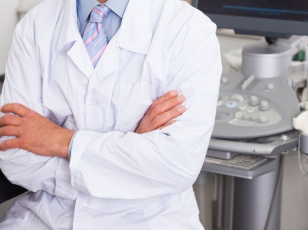 Ritratto di un ecografista professionista seduto con le braccia incrociate in uno studio di diagnostica medica