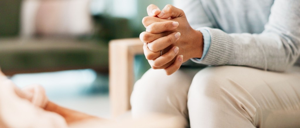 Mani in primo piano di una donna seduta che parla con qualcuno