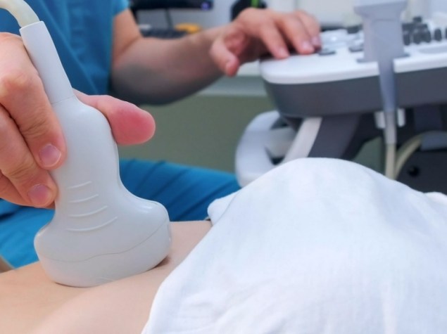 Medico effettua ecografi ai intestinale a un paziente disteso