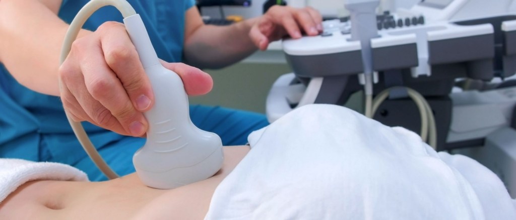 Medico effettua ecografi ai intestinale a un paziente disteso