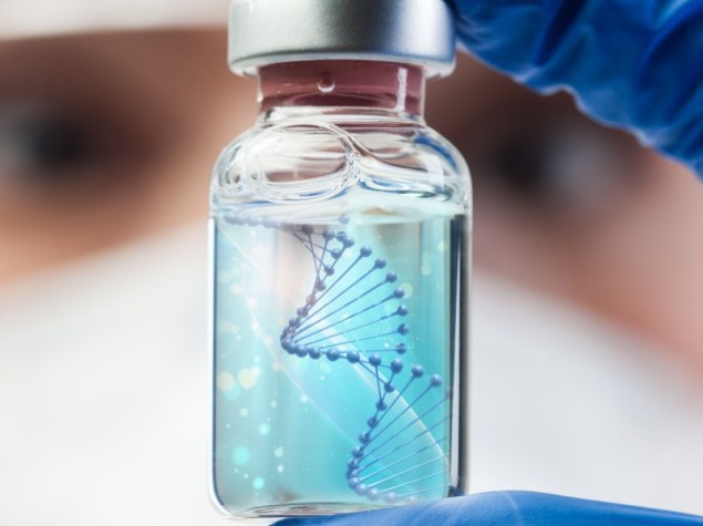 Biotecnologo in laboratorio che tiene una fiala di vetro con filamento di DNA, molecola che forma una doppia elica, tra l'indice e il pollice