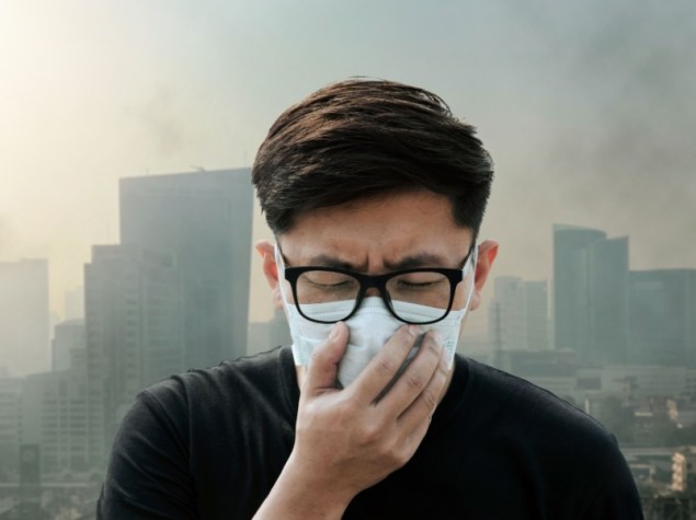uomo con mscherina in città inquinata