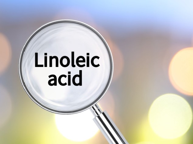 Lente di ingrandimento con testo "Acido linoleico", con luci sfocate visibili sullo sfondo