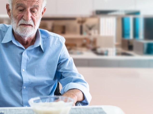 uomo anziano magro senza appetito che osserva una pietanza sul tavolo
