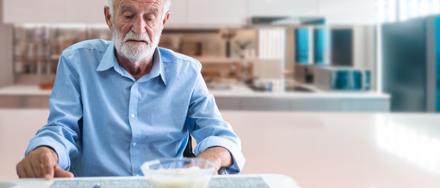 uomo anziano magro senza appetito che osserva una pietanza sul tavolo