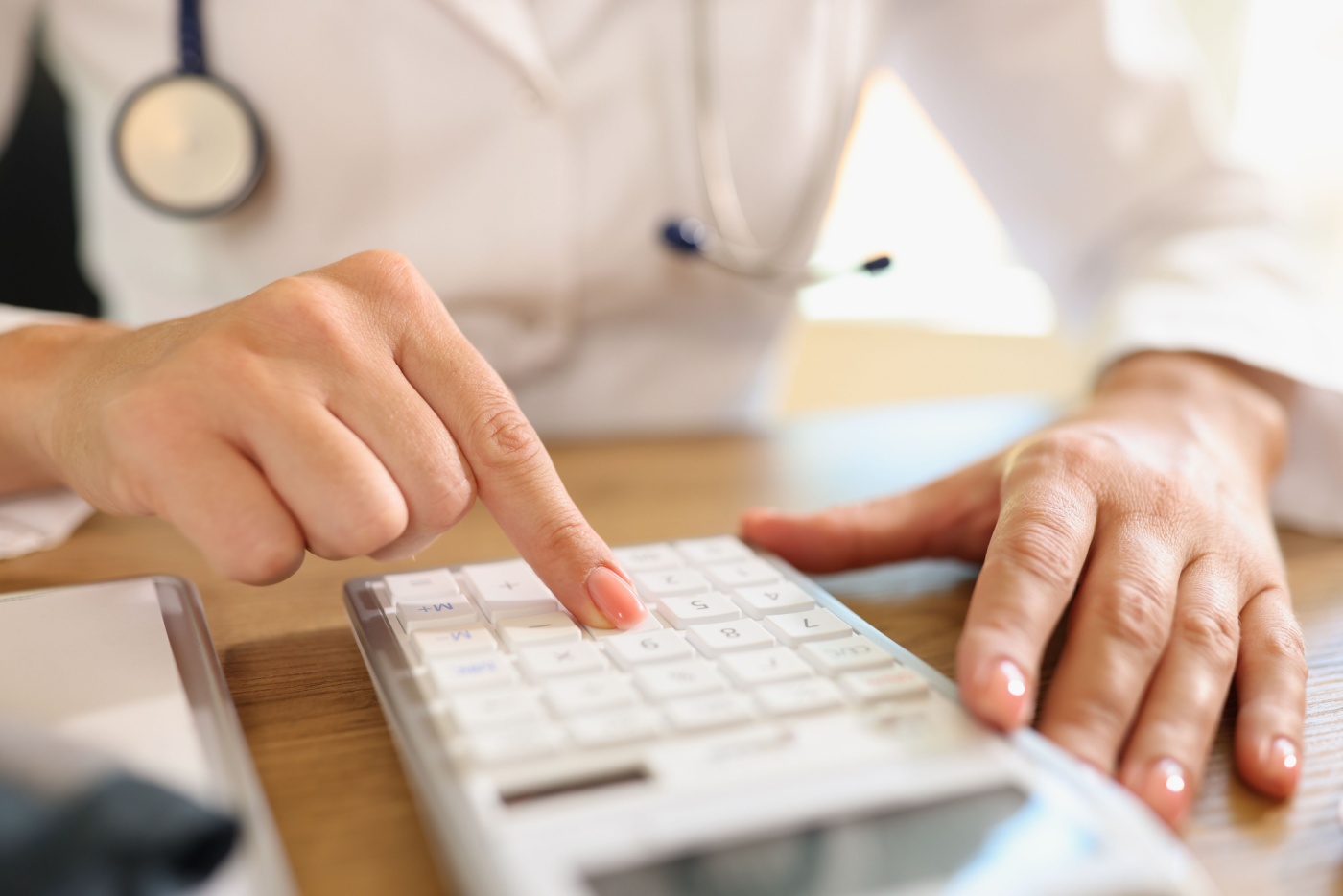 Una dottoressa calcola numeri usando la calcolatrice alla sua scrivania in clinica
