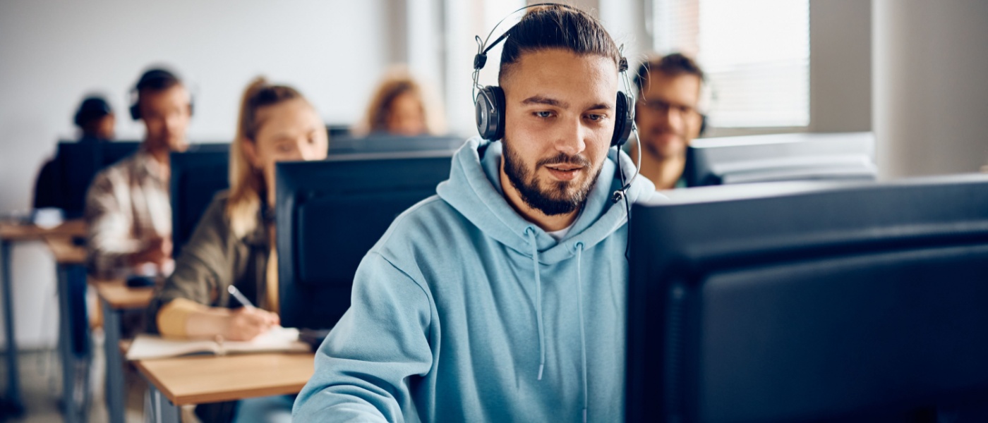 Male student using desktop PC during computer class at the university.