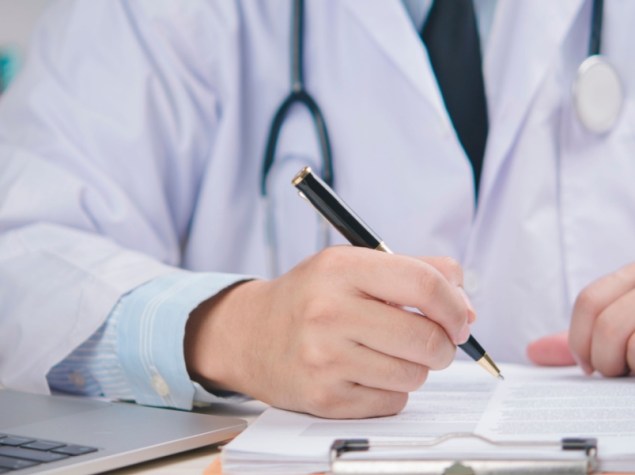 Medico in camice bianco che firma l'accordo medico sulla scrivania