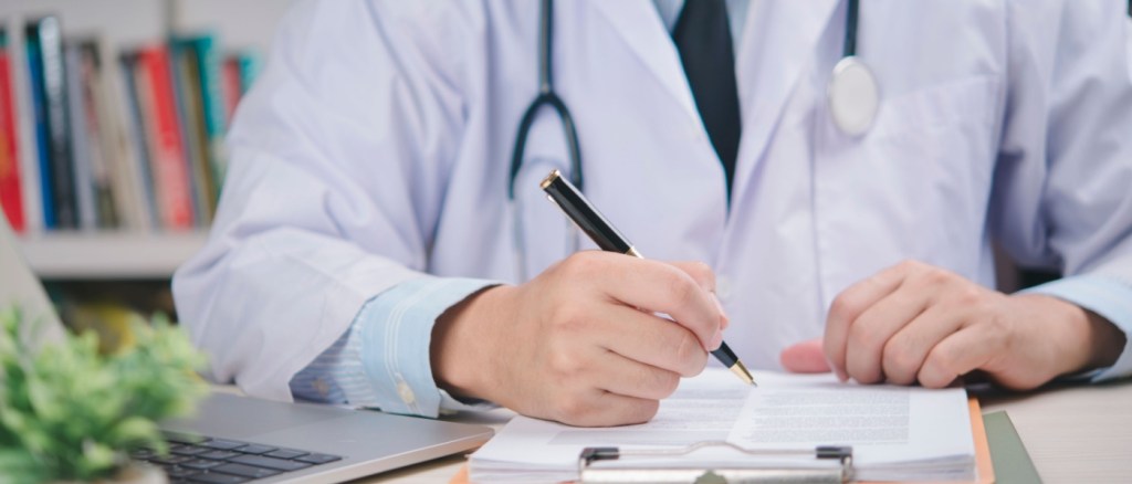 Medico in camice bianco che firma l'accordo medico sulla scrivania