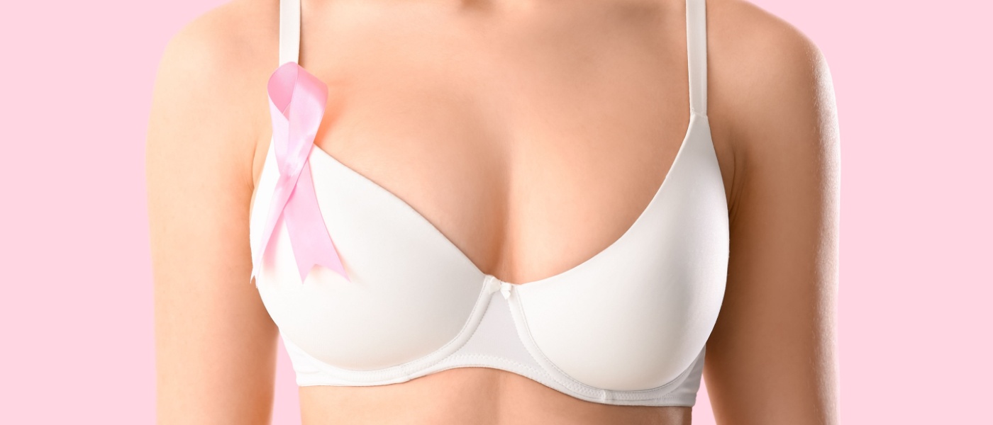 Giovane donna in reggiseno e con nastro di sensibilizzazione su sfondo rosa