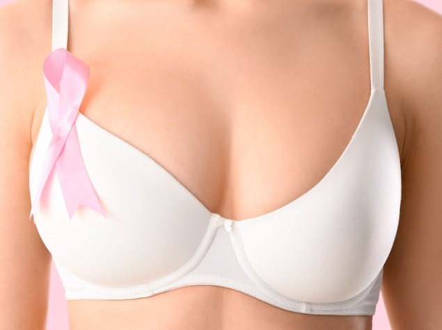 Giovane donna in reggiseno e con nastro di sensibilizzazione su sfondo rosa