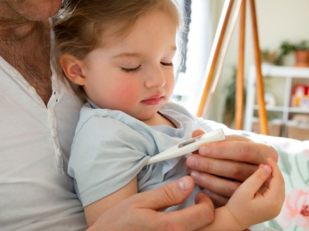 Padre che controlla la temperatura del bambino malato a casa