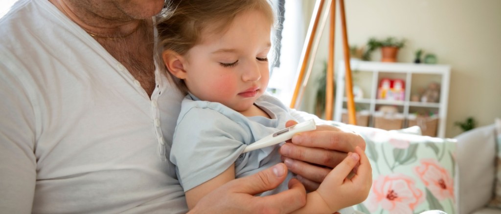 Padre che controlla la temperatura del bambino malato a casa