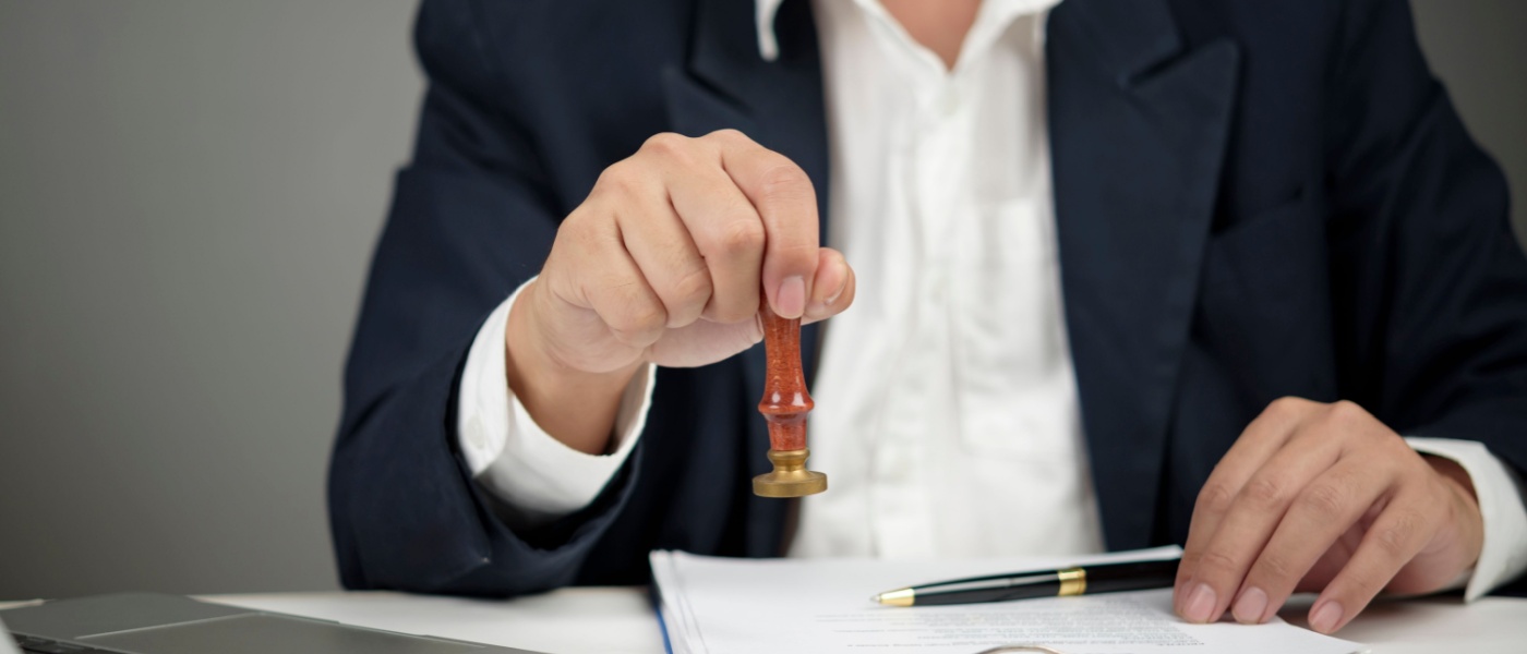 Mano del manager con un timbro per l'approvazione finale del documento aziendale