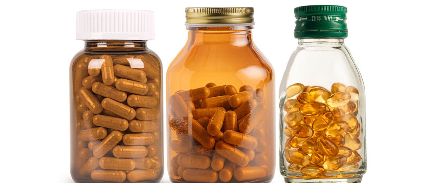 Set di bottiglie di vetro di integratori e vitamine isolate su sfondo bianco