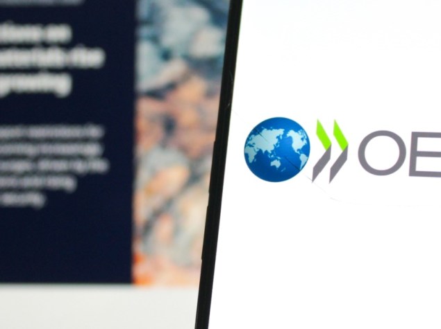 Logo dell'OCSE visualizzato su un telefono cellulare con il sito web ufficiale dell'OCSE sullo sfondo