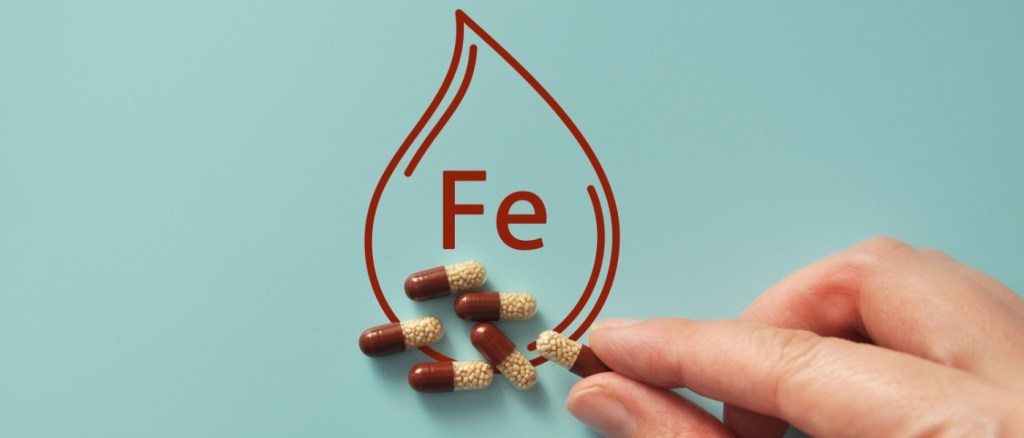 Concetto dell'integratore di ferro con le pillole e l'icona della goccia