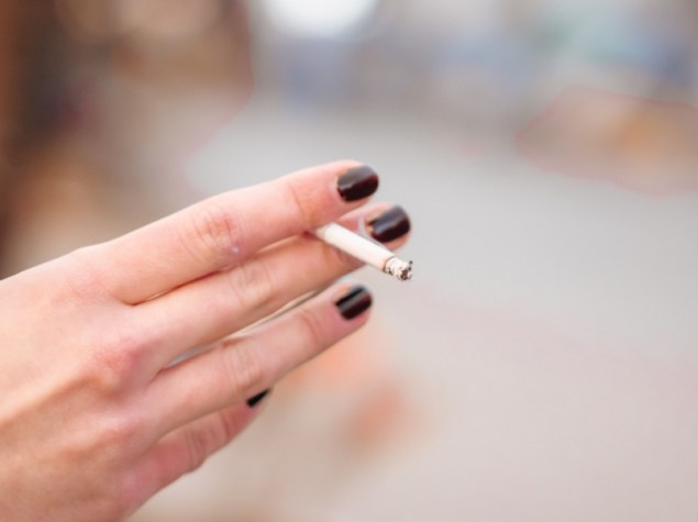 Mano di donna che tiene una sigaretta per strada