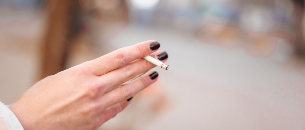 Mano di donna che tiene una sigaretta per strada