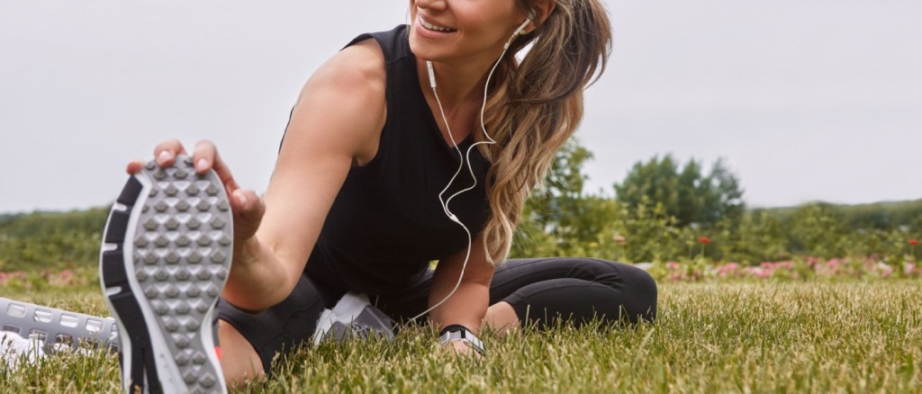 donna felice che fa stretching con auricolari