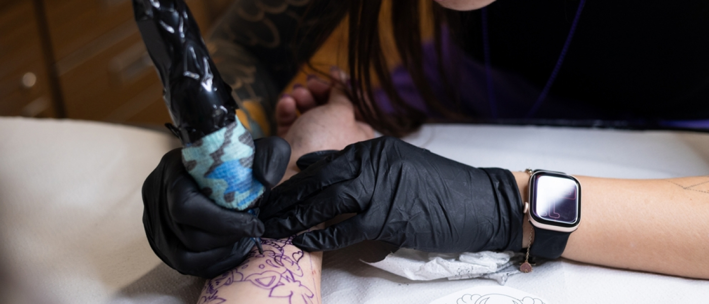 tatuatore che esegue un tatuaggio sul braccio di un cliente