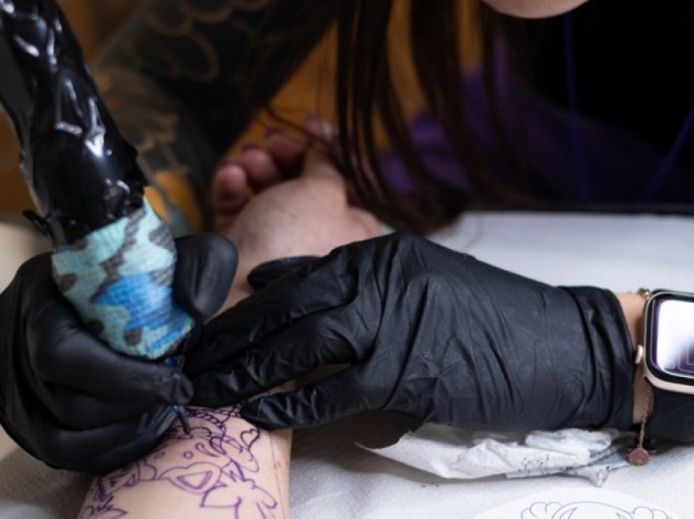 tatuatore che esegue un tatuaggio sul braccio di un cliente