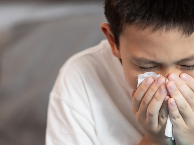Sick child boy having allergies,hay fever,runny nose,sneezing,nasal congestion,blow the nose with tissue paper,inflammation of a nasal sinus,allergic rhinitis,seasonal allergy or dust,air pollution