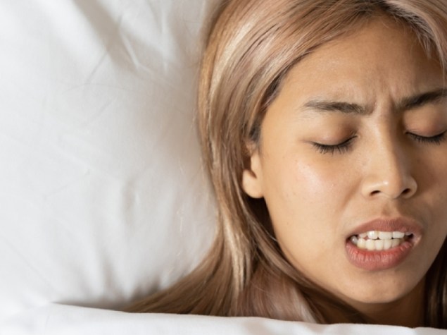 Tired and stressed Asian woman with colored hair sleeping, having bad dream, nightmare with bruxism or grinding teeth