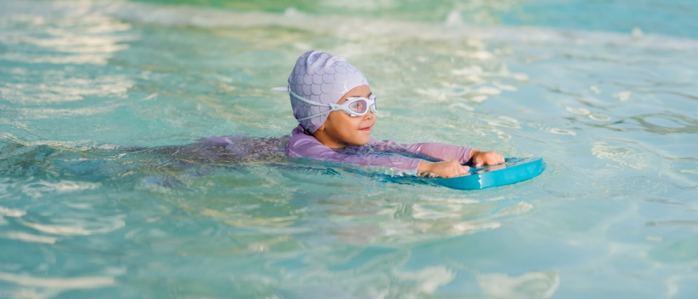 Bambino in età prescolare che impara a nuotare con il bordo in piscina