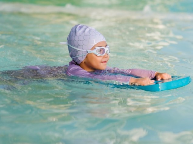 Bambino in età prescolare che impara a nuotare con il bordo in piscina